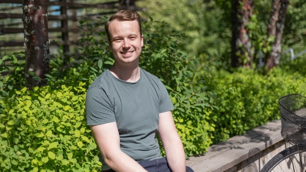 Foto på Anton Degerfeldt sittande med buskar och spaljé i bakgrunden
