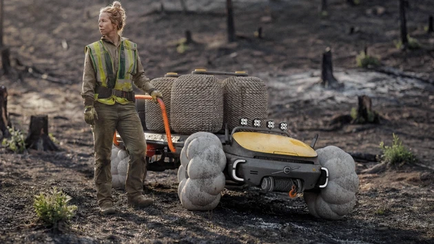 En kvinna som står bredvid en brandbil i skogen.