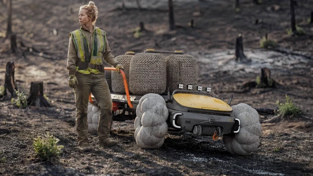 En kvinna som står bredvid en brandbil i skogen.