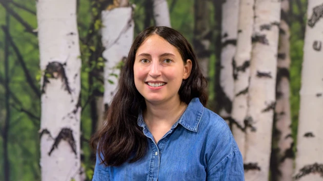 A woman standing in front of a painting of trees