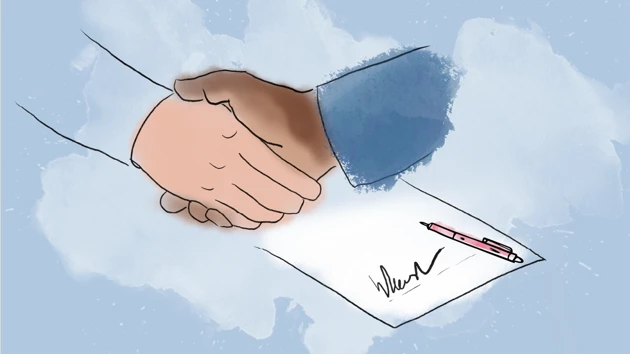 Two hands shaking over a signed paper.