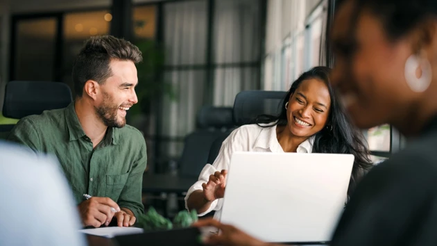 Glada personer i samtal vid en dator.