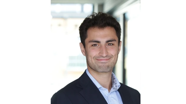 Daniel Ghazi i kostym ler mot kameran.