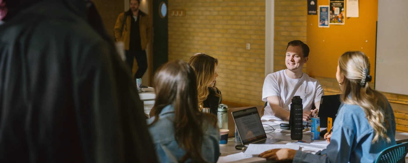 Studenter sitter vid ett bord och pluggar och pratar med varandra