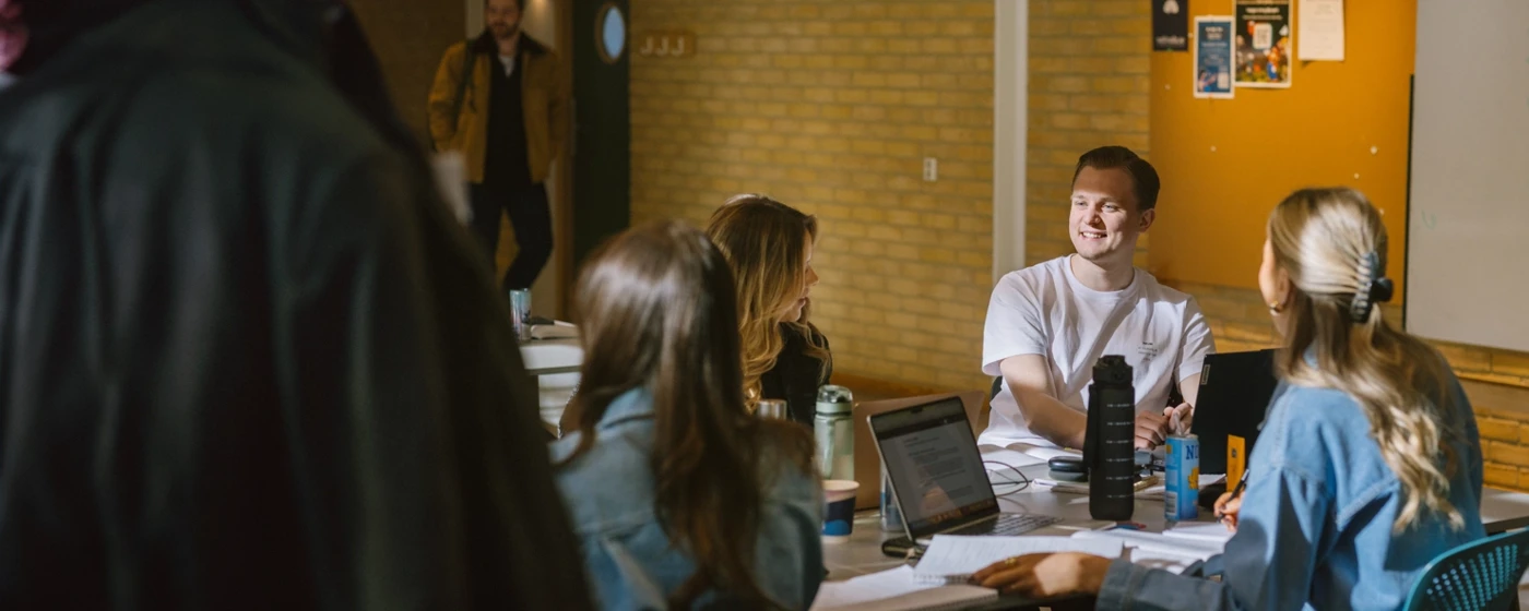Students sitting at a table, studying and talking to each other