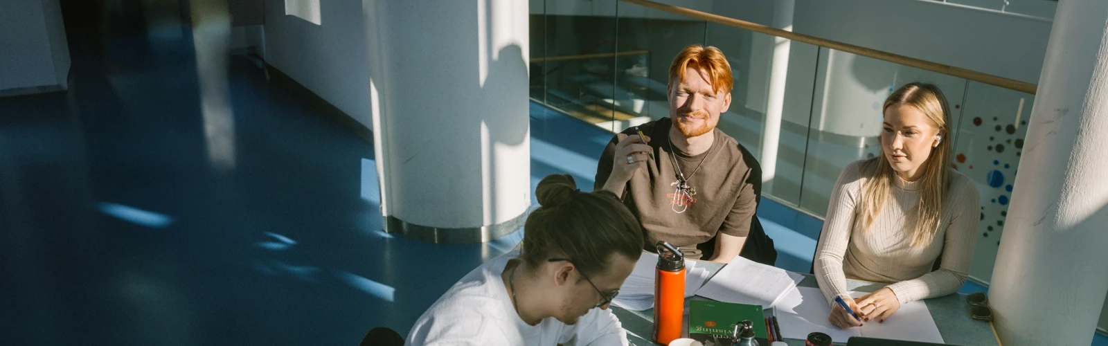 Tre personer sitter vid ett bord och pluggar.