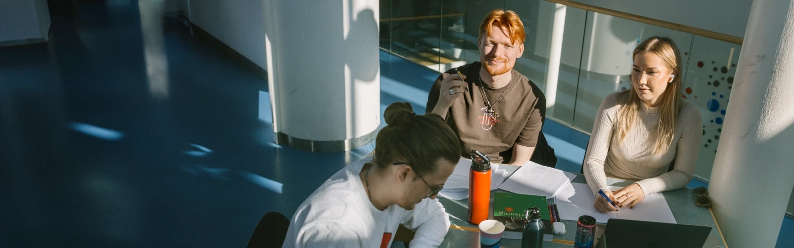 Tre personer sitter vid ett bord och pluggar.