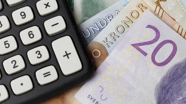 A calculator and a pile of Swedish bills. 