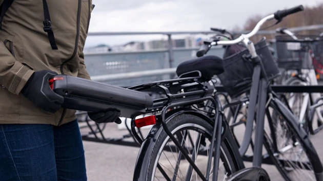 Person som sätter in ett batteri i en elcykel