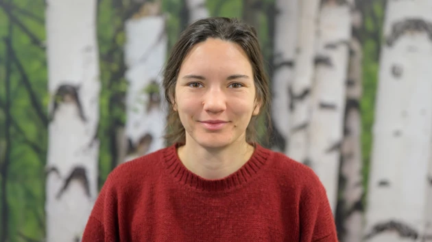 En kvinna  framför en björk tapetbakgrund