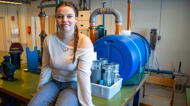 Foto på Emma Björ sittande på ett bord i energteknikprogrammets labblokal