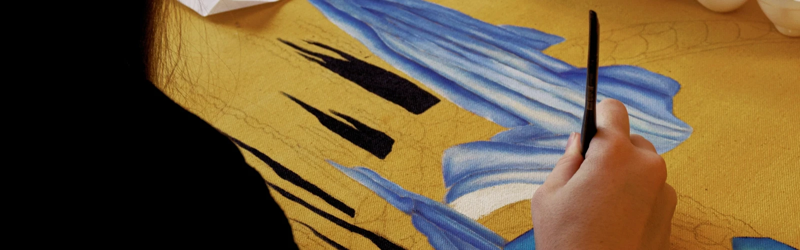 En person målar en tavla på ett bord.