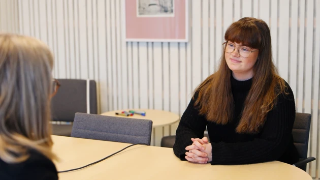 En student sitter vid ett bord och pratar med en kvinna. 