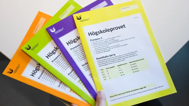 En hand håller ett antal högskoleprov.