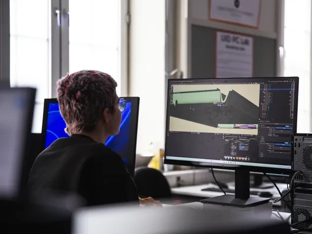 Photo of three master's students working on protypes on a table