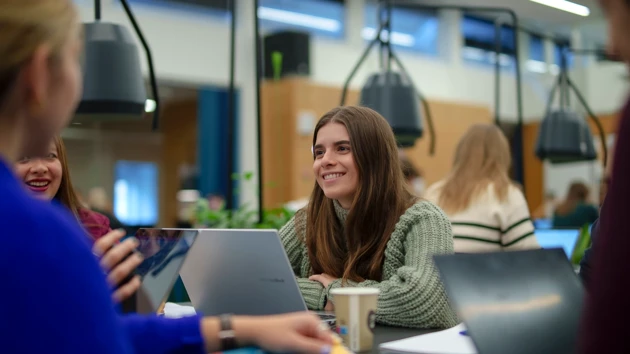 A happy student is interacting with others in a cosy study space.
