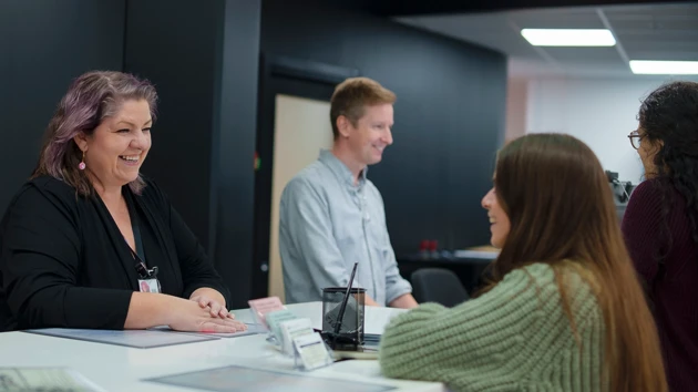 Staff welcoming new students and providing support at the infocenter service desk.