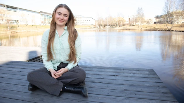 Porträttfoto av Johanna Birgersdotter, i bakgrunden dammen på campus