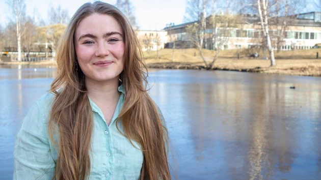 Porträttfoto av Johanna Birgersdotter, i bakgrunden dammen på campus
