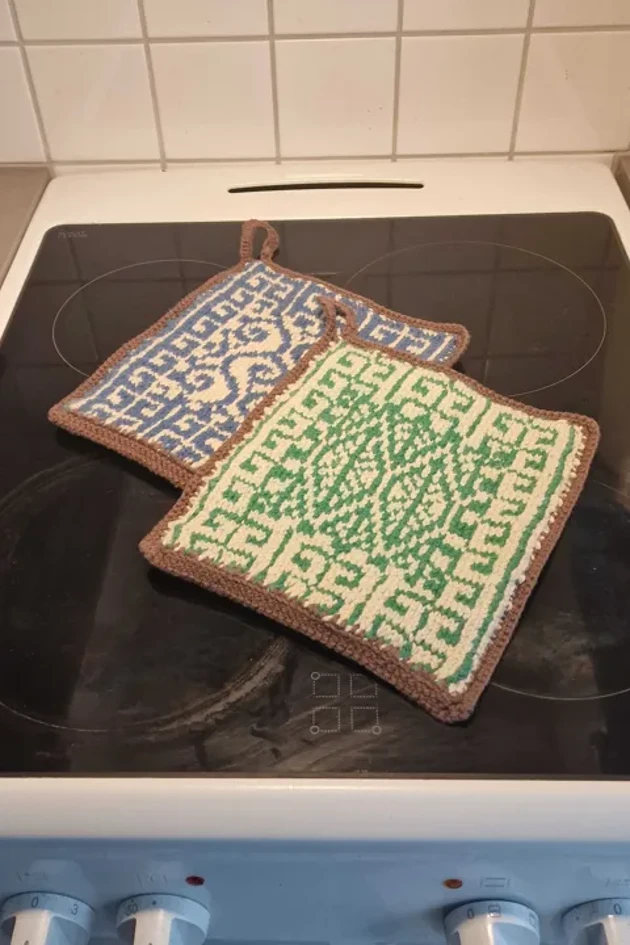 En spishäll med grytlappar på.