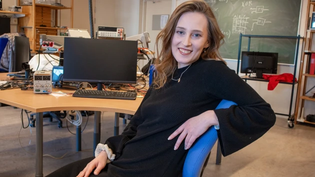 Bild på Julia Eklund sittande vid arbetsbord i elektroniklabb
