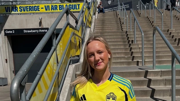 En kvinna i landslagströja står på en trappa.