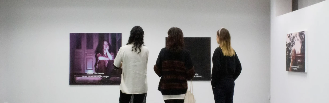 Tre personer i ett galleri som tittar på bilder