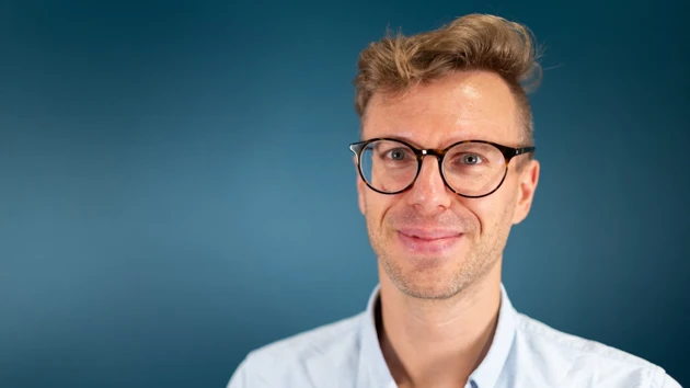 A man wearing glasses and a blue shirt.