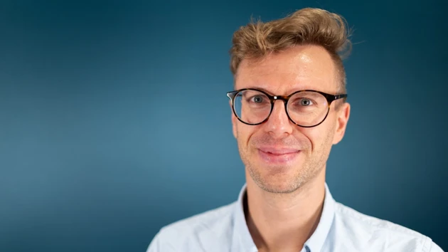 A man wearing glasses and a blue shirt.