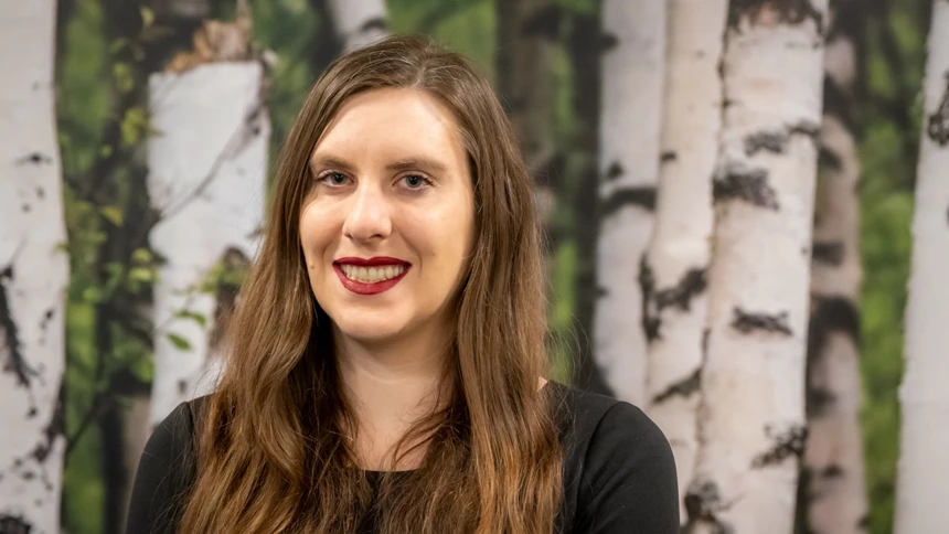 A woman with long hair standing in front of trees