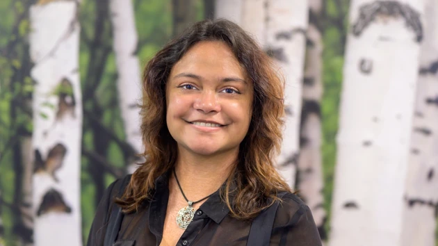 A woman standing in front of a painting of trees