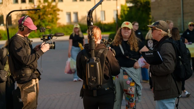 Två personer med kamera filmar en student. 