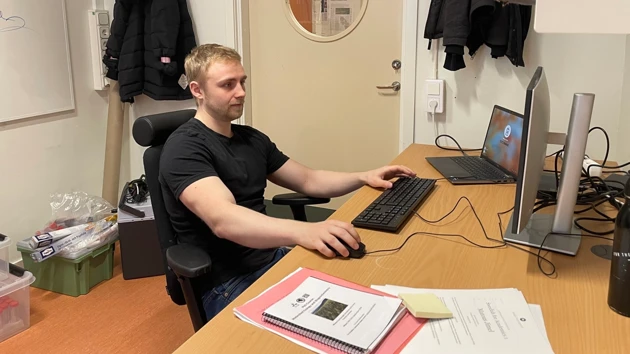 Bild på Matous Jimel sittande vid skrivbordet i sitt arbetsrum.