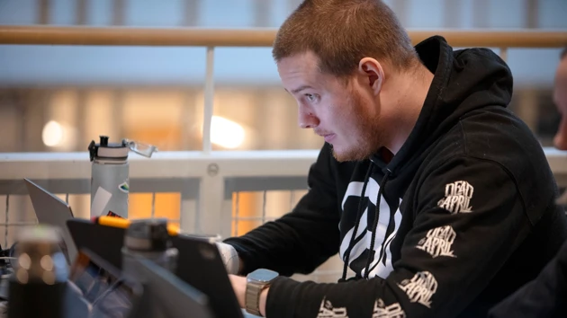 A man sitting at a table using a laptop computer.