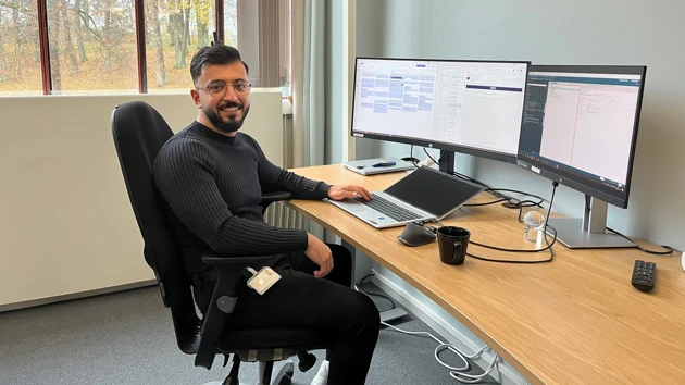 Bild på Mohammad Mshaleh sittande vid datorn på sin arbetsplats Siemens Energy