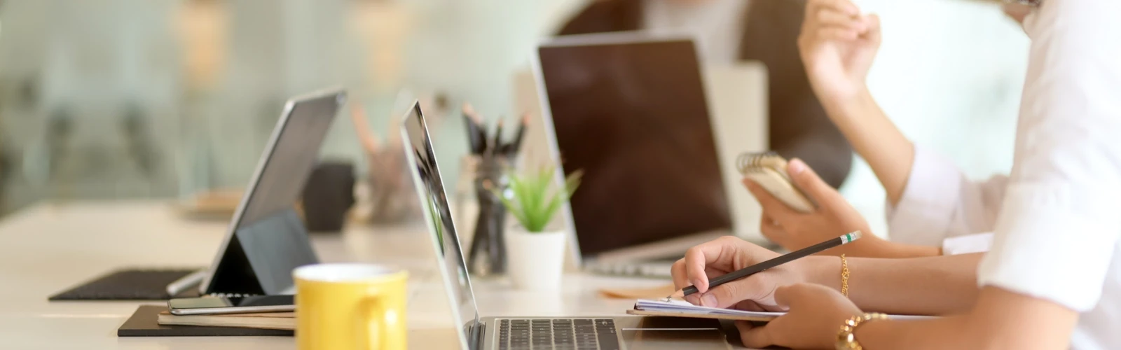 Detaljbild från ett mötesrum med personer och datorer.