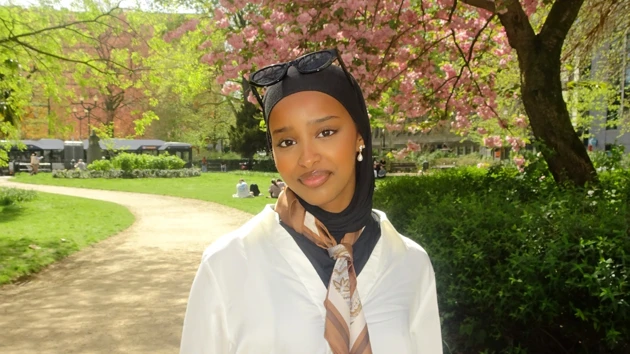 Najma Jama Issa med en park i bakgrunden med blommande träd.