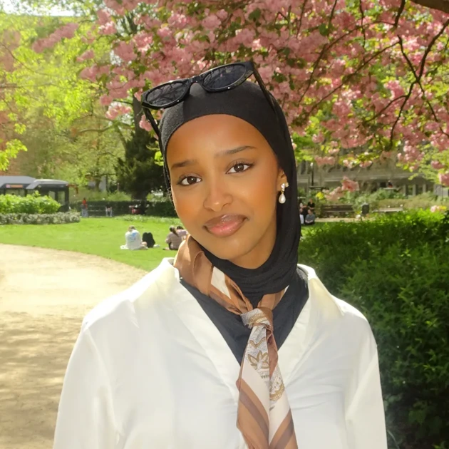 Najma Jama Issa med en park i bakgrunden med blommande träd.