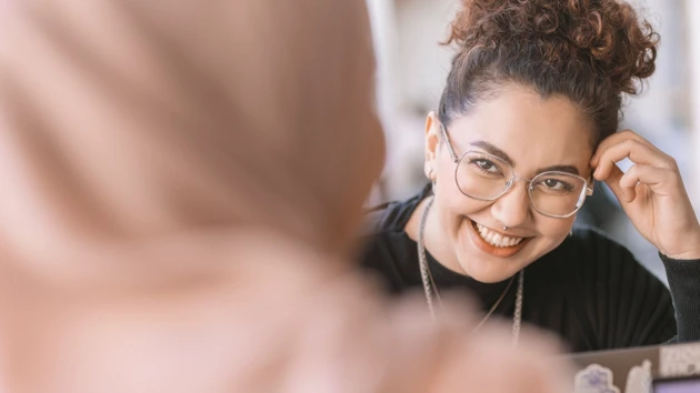 En leende kvinna som stöder studenter som har frågor om sin utbildning.