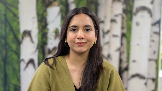 En kvinna står framför en målning med träd