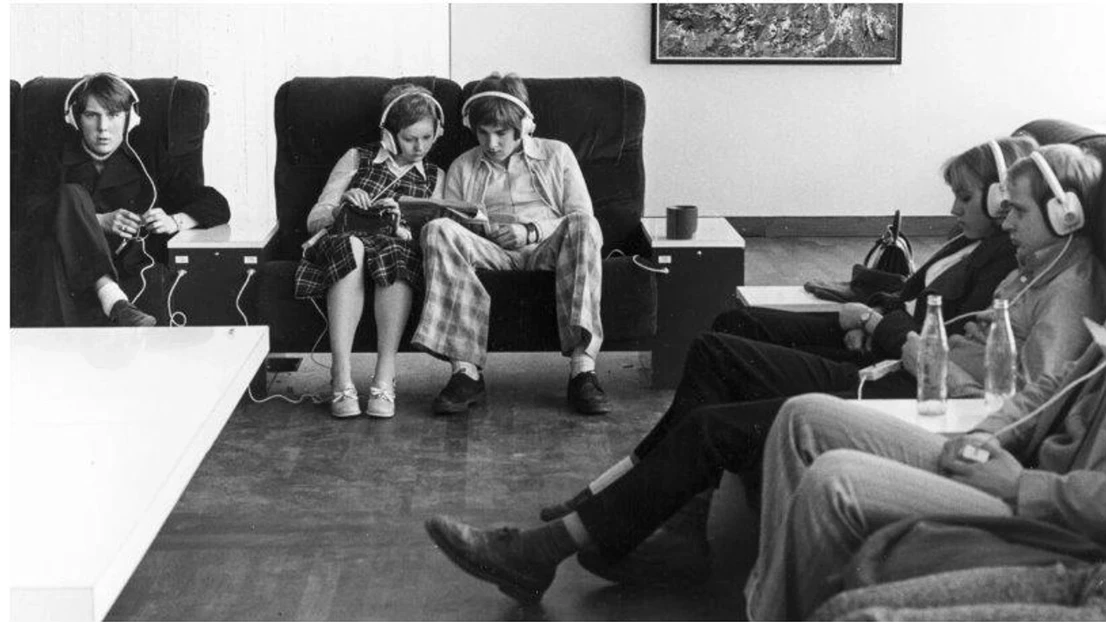 People sitting in armchairs listening through headphones