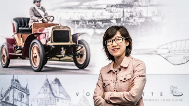 Bild på Yuhan Zhang stående framför vägg med historiska bilfoton.