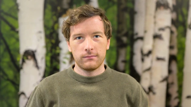A man standing in front of a birch forest wallpaper background