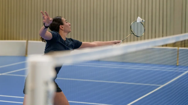 Kvinna spelar badminton.