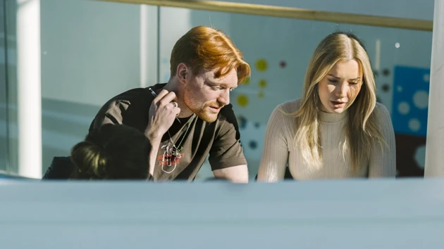 Två studenter har hittat en solig plats att jobba med sitt grupparbete på.