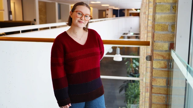 Student som står framför en vägg i Lindellhallen. 