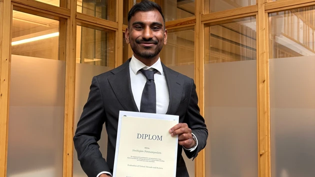 Foto på Sintjujan Ponnampalam som håller upp sitt examensdiplom