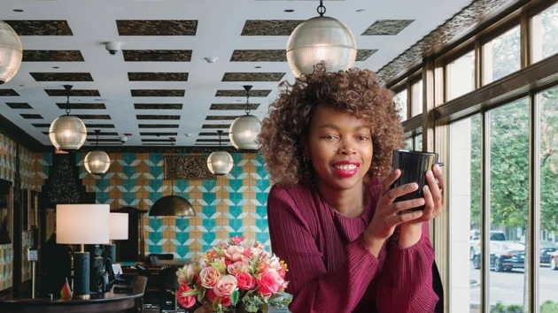Kvinnlig student håller i en kaffekopp vid ett bord.