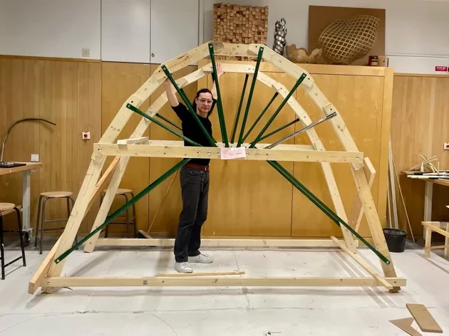 Julio Diarte står i en byggd träställning, inne i en verkstad.