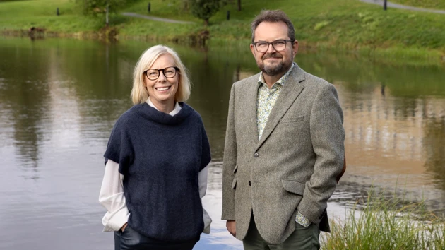 En man och en kvinna som står bredvid ett vattendrag.